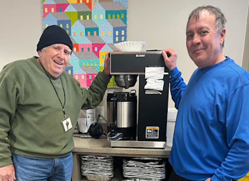 2 program volunteers standing near a Bunn Coffee Maker